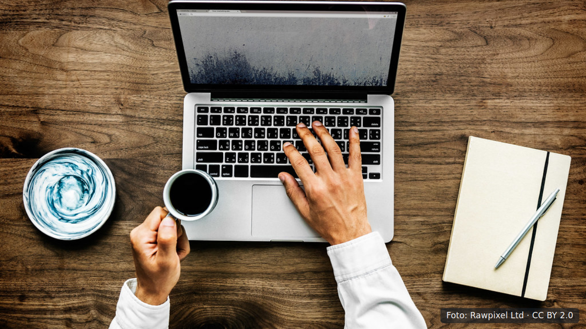 Bovenaanzicht van man die op laptop werkt aan houten tafel